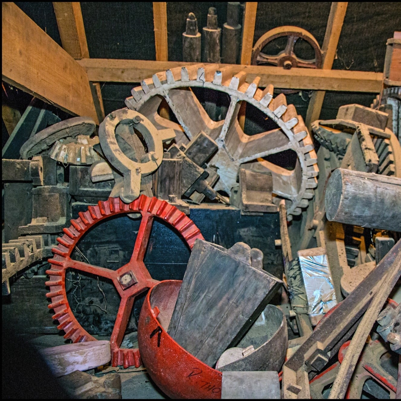 A jumble of metal cogs and other pieces of metal. A prominent red cog is at the front of the image. 