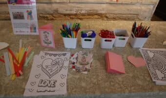 Pens and paper on a table for family activites. There is a colouring in sheet that says LOVE in large letters.